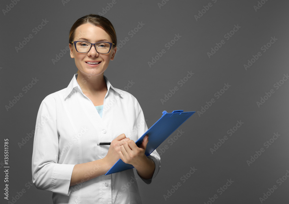 Young doctor with clipboard on grey background Young doctor with clipboard on grey background