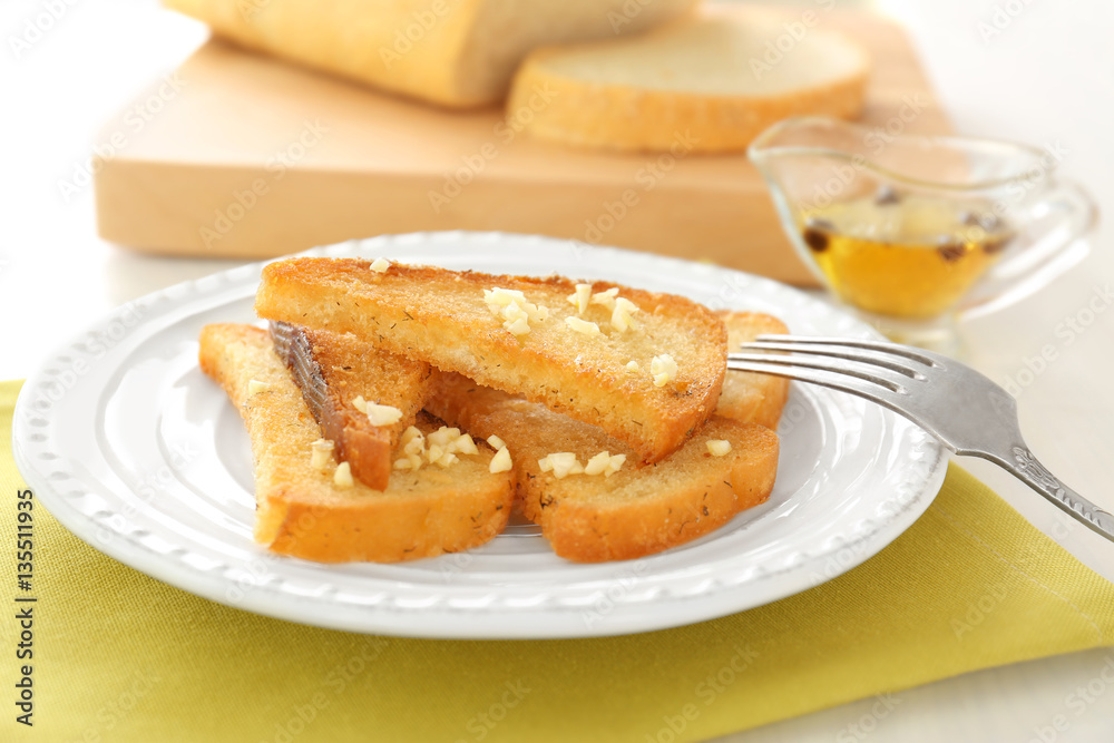 Plate with tasty garlic French bread slices on napkin Plate with tasty garlic French bread slices on napkin