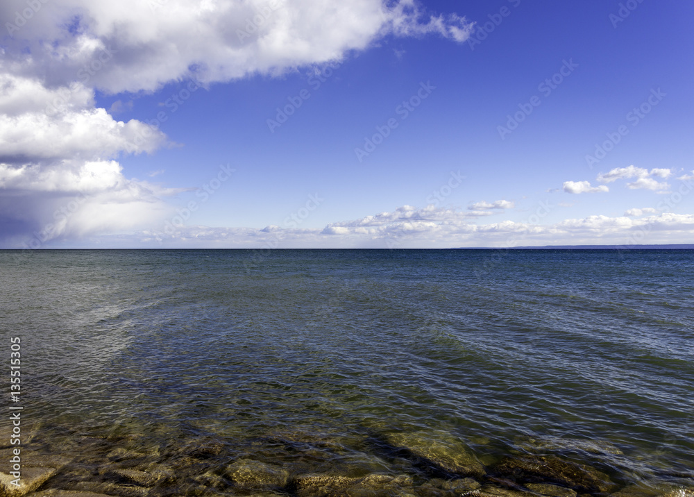Vibrant blue green lake with gentle waves, rocky shoreline,
