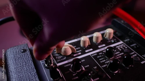 Man's hand inserts cable jack in guitar amp