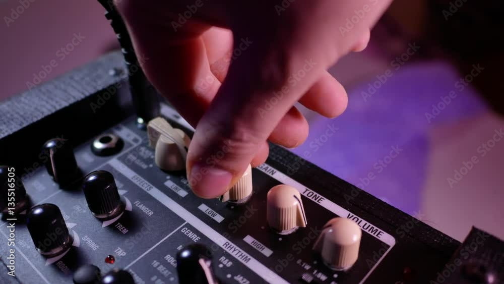 Man's hand increases the volume on the guitar amp Man's hand increases the volume on the guitar amp