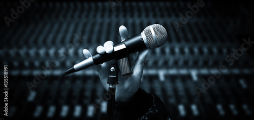 Foto singer hands holding microphone on studio mixer background
