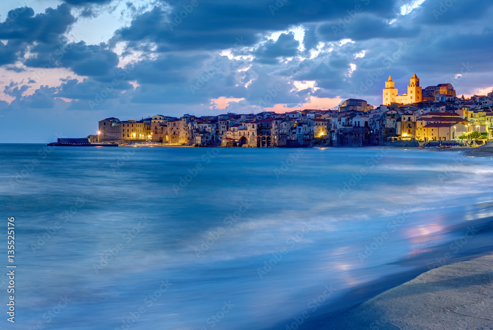 The city of Cefalu in Sicily and the local beach at dusk