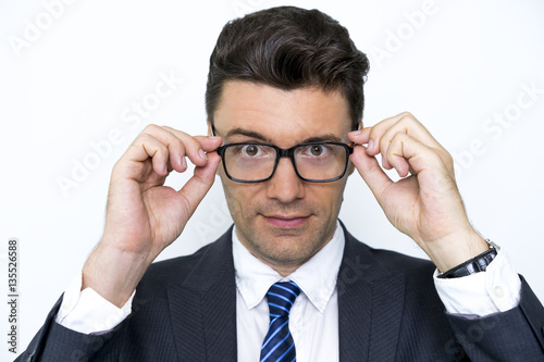 Confident young businessman putting on glasses