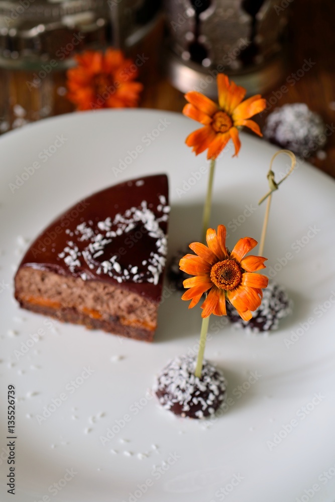 Bright orange flower and chocolate dessert on the plate. Selective focus.
