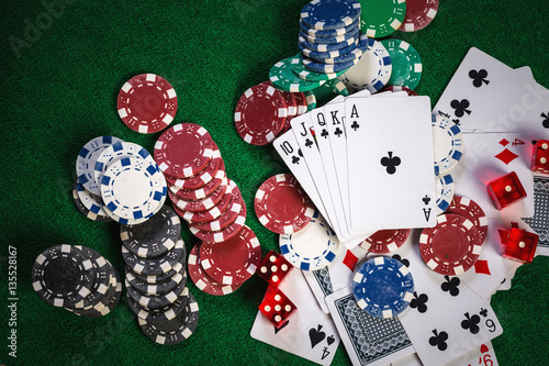 Poker chips and cards on casino gamble green table with royal fl