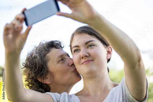 Smiling teenage girl taking selfie with mother