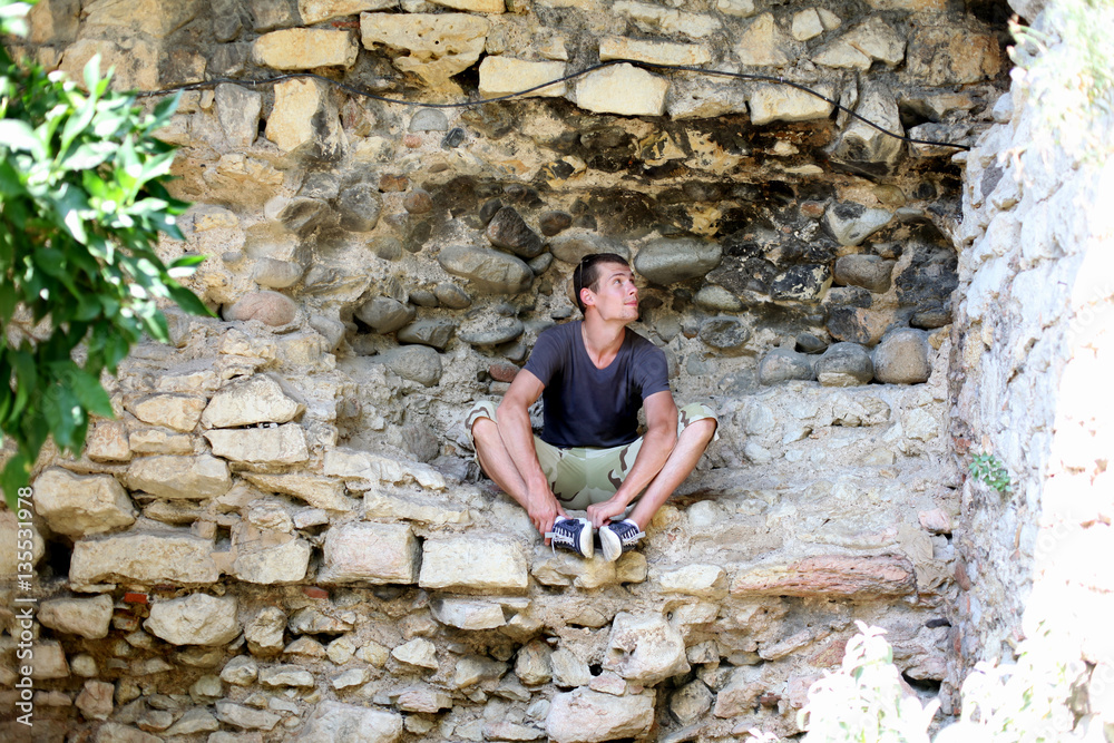 A male traveler sits on a stone A male traveler sits on a stone