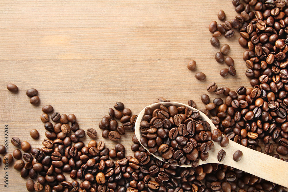 Handful of roasted coffee on a wooden table with a spoon. Handful of roasted coffee on a wooden table with a spoon.