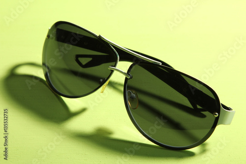 The black sunglasses lying on a green background.