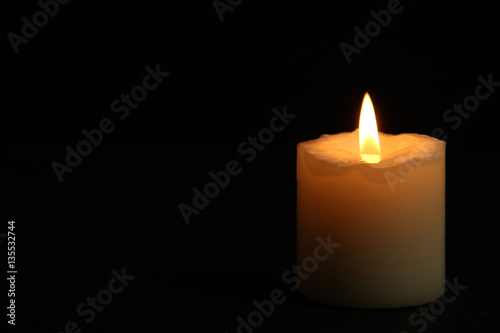 Canvas-taulu Сandle burning brightly in the black background.