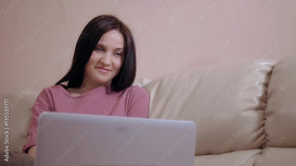 Young Brunette Girl In a Warm Socks Stockings, Lays On Leather Sofa at Home And Working On Laptop Young Brunette Girl In a Warm Socks Stockings, Lays On Leather Sofa at Home And Working On Laptop