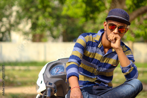 Fototapeta Naklejka Na Ścianę i Meble -  Asian Male Model Is Sitting On The Bike He Is A Wear A Sunglasses With The Cap 
