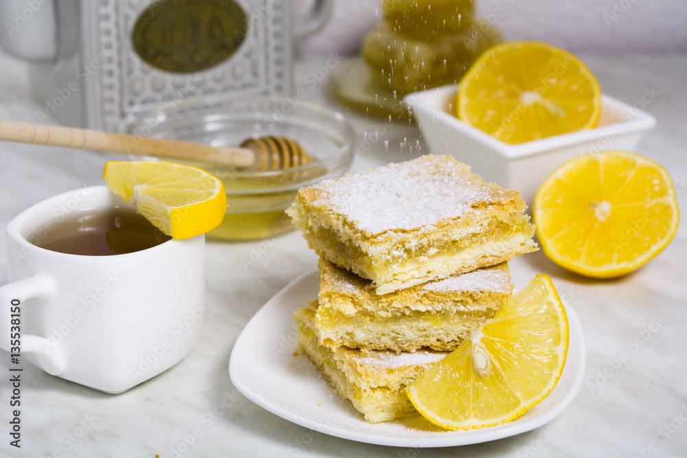 Three pieces of lemon pie with fresh lemon and cup of tea and teapot on the background Three pieces of lemon pie with fresh lemon and cup of tea and teapot on the background
