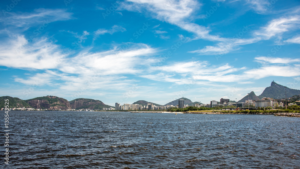 View of Guanabara Bay at sunny day with blue sky, white spindrift clouds and Christ the Redeemer on the background in the city of Rio De Janeiro, Brazil
