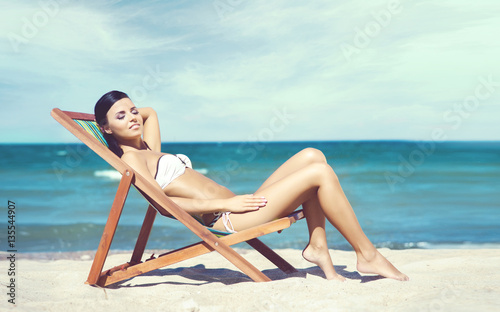Young, beautiful and sexy woman relaxing on a summer beach