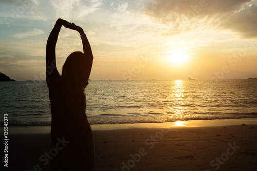 silhouette of woman pointing with finger in sky on the beach