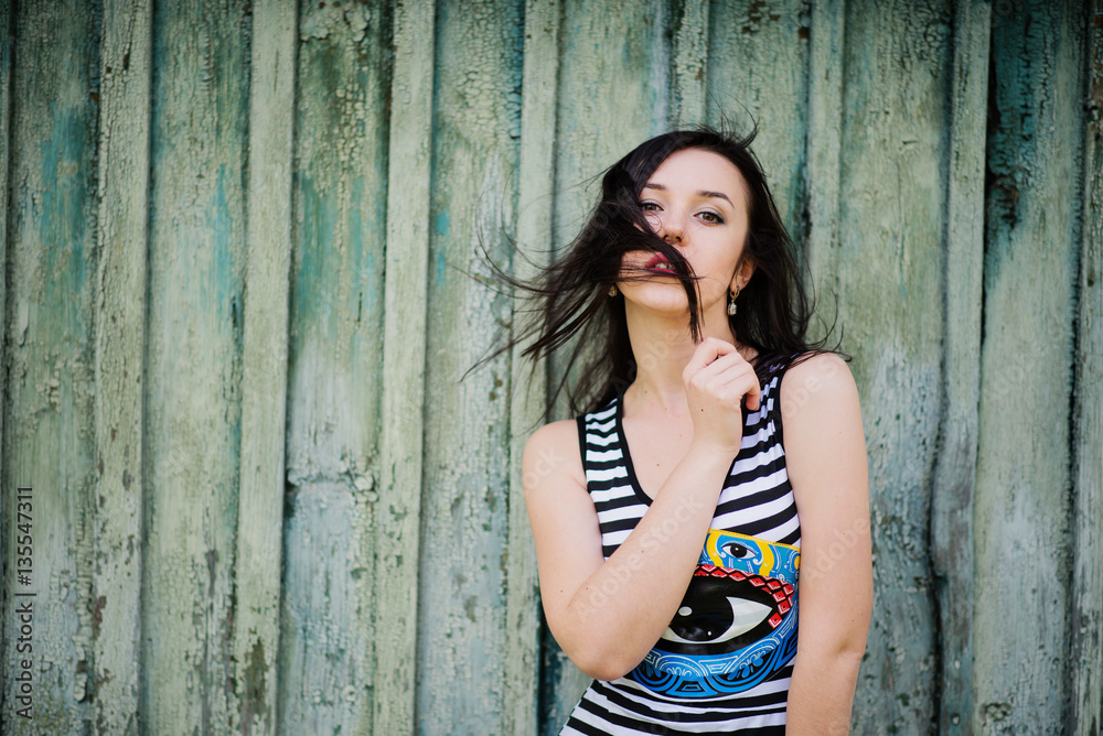 Brunette model girl at dress with stripes background cian wooden Brunette model girl at dress with stripes background cian wooden