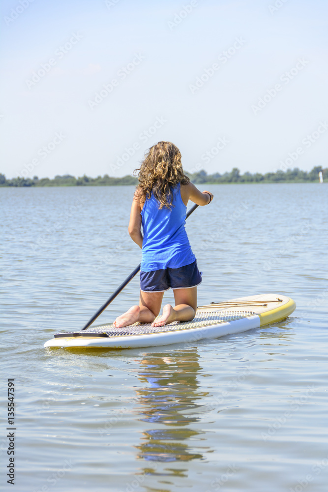 Teenager paddelt auf dem Board über den See