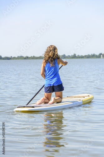 Teenager paddelt auf dem Board über den See