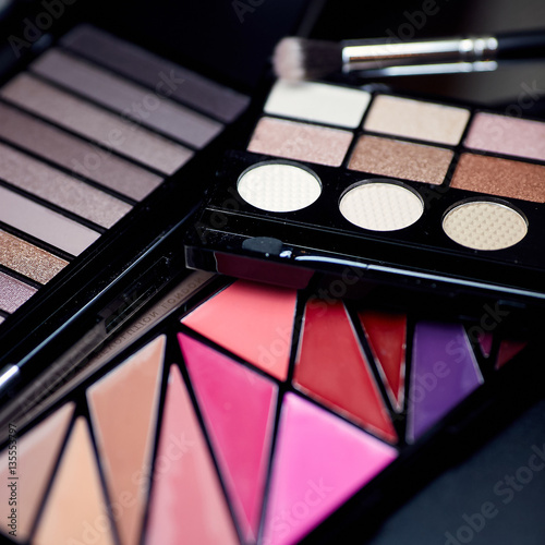 Colorful makeup palette and brush to apply powder. on pure black background.
