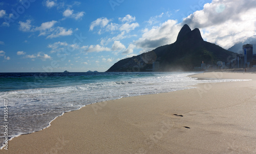 Afternoon at Ipanema beach, Rio de Janeiro, Brazil. The sea, the beach, the blue sky with clouds and the hill two brothers in the background.