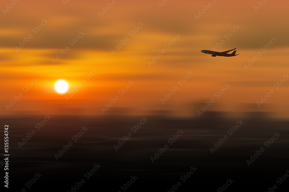 Silhouette of airplane flying in a sky over the city at sunset