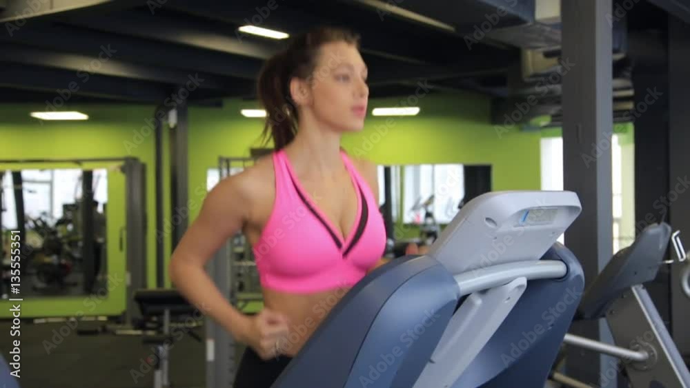 Attractive young girl running on the treadmill in the gym. Fitness concept. Attractive young girl running on the treadmill in the gym. Fitness concept.
