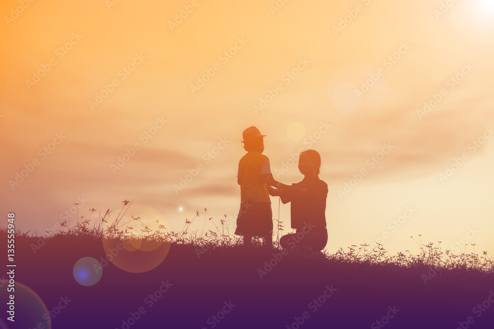 Mother encouraged her son outdoors at sunset, silhouette concept