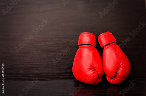 Two red boxing gloves on the side of the frame on a black background, empty space