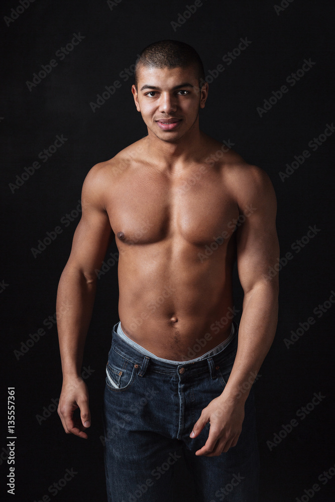Fototapeta premium Cheerful young african sportsman posing over black background