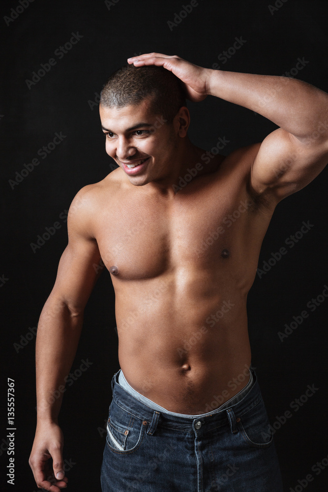 Smiling young african sportsman posing over black background