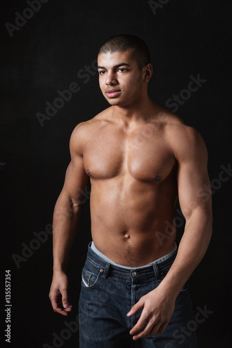 Happy young african sportsman posing over black background
