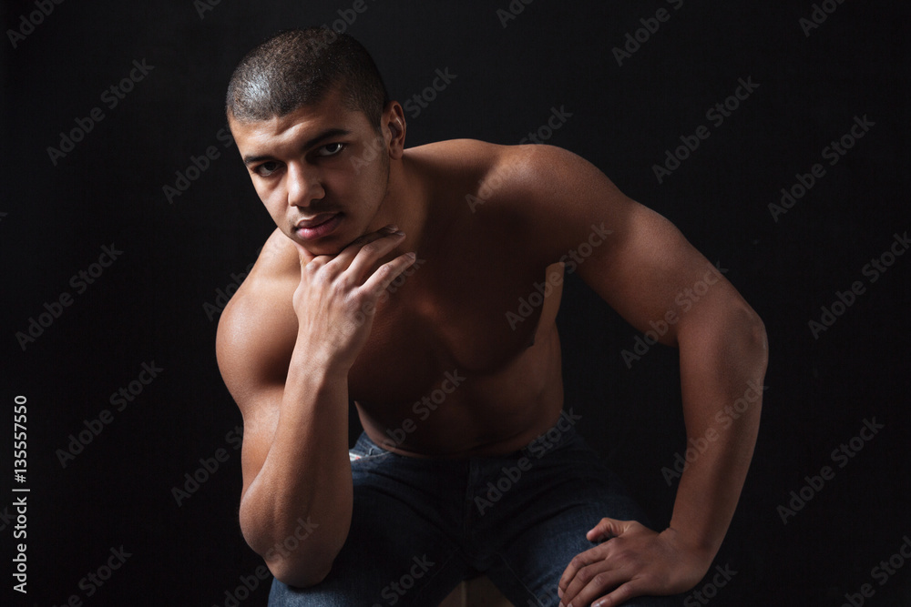 Young african sportsman sitting over black background Young african sportsman sitting over black background