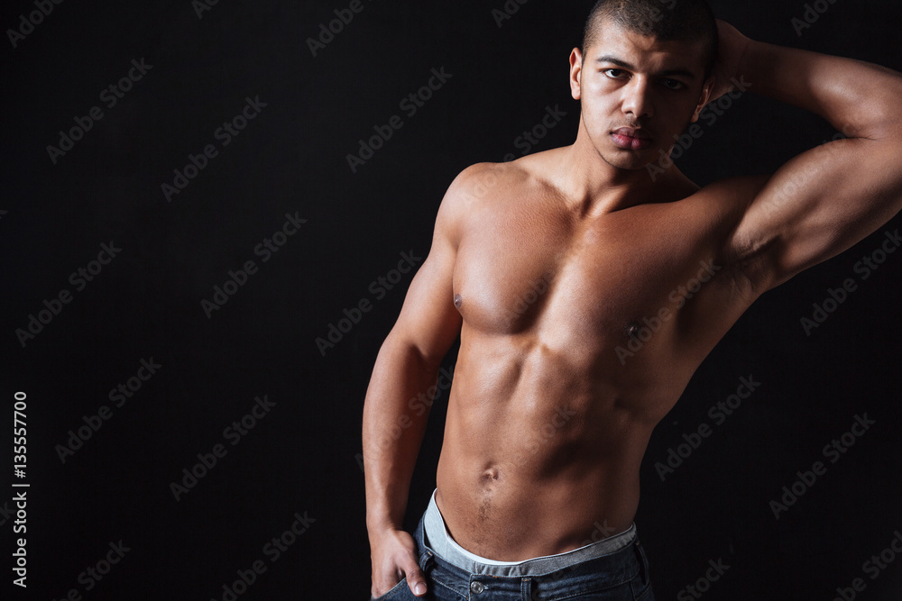 Fototapeta premium Attractive sportsman posing over black background