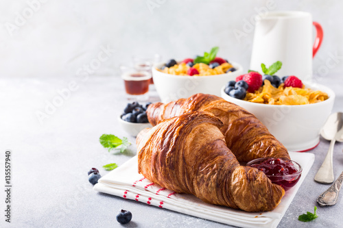 Croissants, corn flakes and berries on light gray background. Copy space. Healthy breakfast concept.