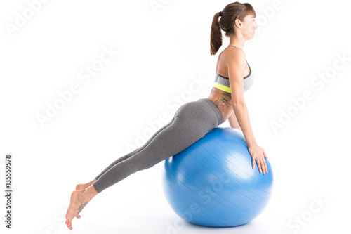 Beautiful fitness woman doing pilates exercises with fit ball. Isolated on white.