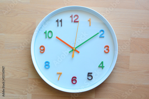 The colorful clock on the wooden floor background.