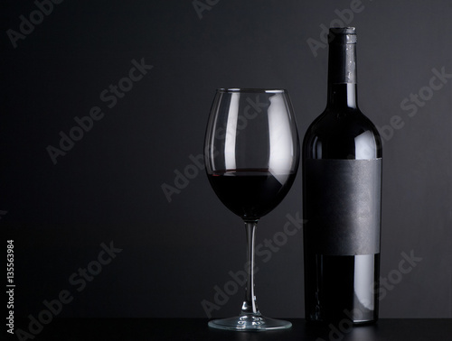 bottle red of wine with a glass on a black background