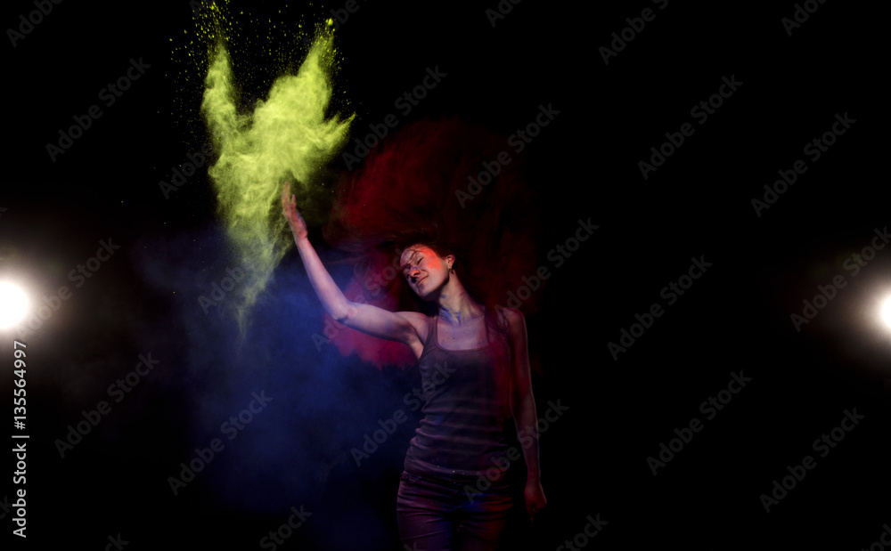 Girl throws yellow powder paint holly from which is formed a cloud. Above the girl's head a cloud of red paint holy, which she did with the help of his long hair.