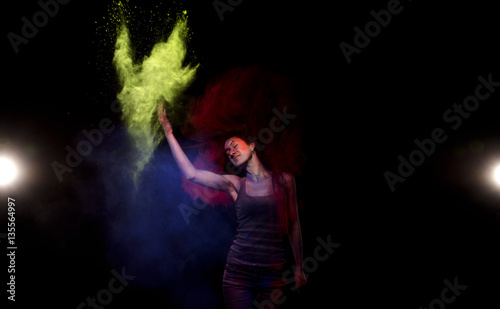 Girl throws yellow powder paint holly from which is formed a cloud. Above the girl's head a cloud of red paint holy, which she did with the help of his long hair.