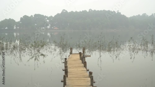 Magical misty dawn. Wooden bridge in the misty lake photo