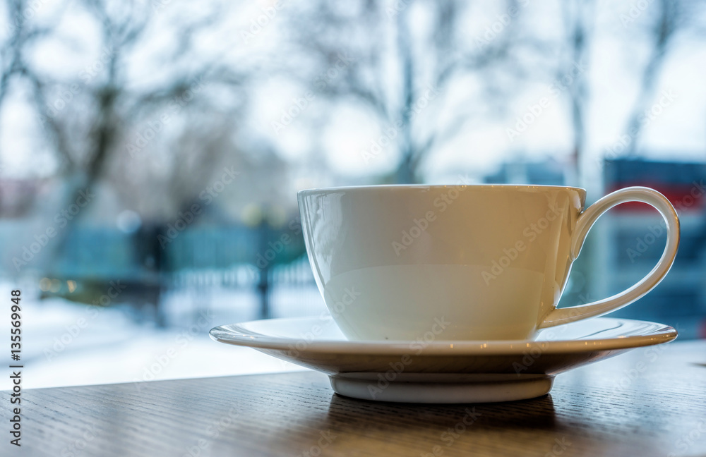 White tea cup on a wooden table. Winter snow background White tea cup on a wooden table. Winter snow background