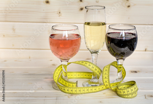 glasses of wine and champagne with  measuring tape.Calories in alcohol are extra-fattening 