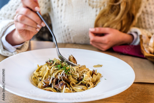 Woman eating Fresh delicious Mushroom pasta in a white plate