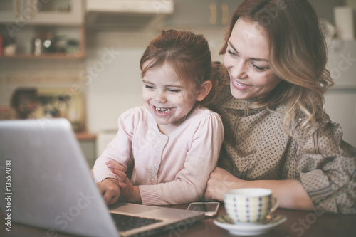 Mother with daughter using laptop.