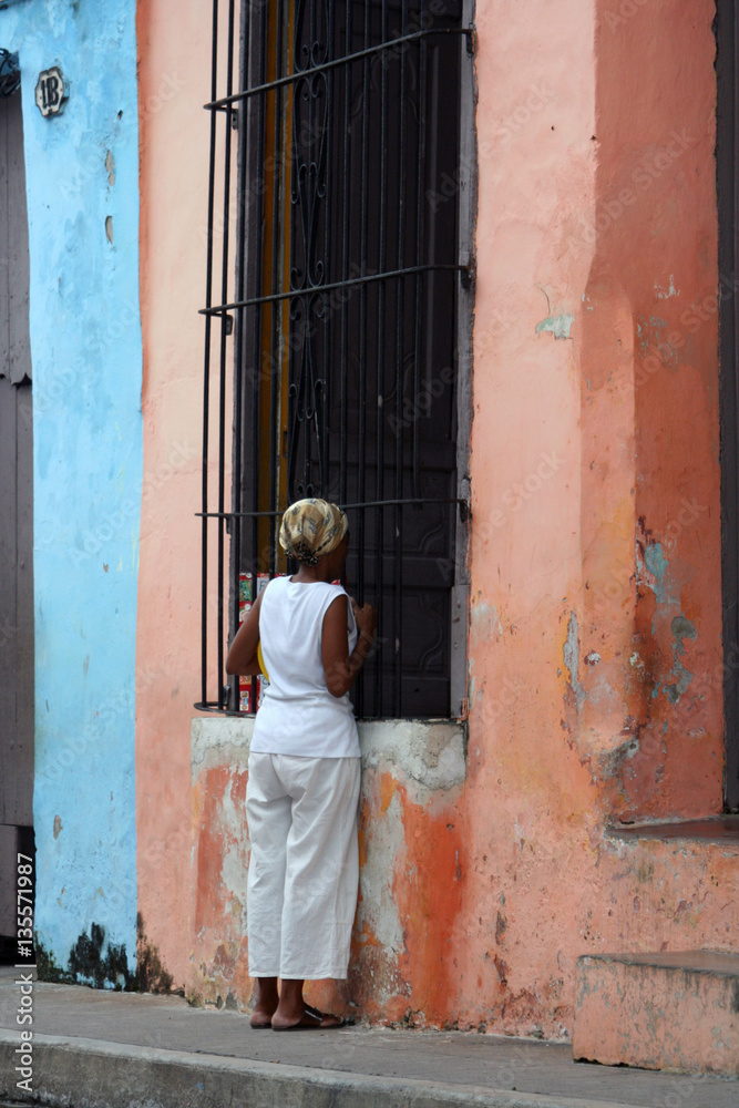 Cuban woman talk to other person through the window