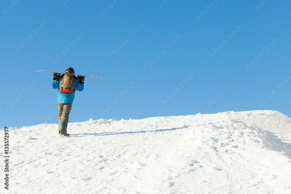 Snowboarder in helmet taking a walk to the top of a mountain
