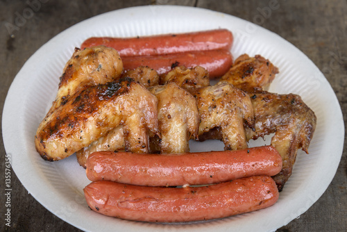 Grilled marinated chicken sausages and wings on white polystyren
