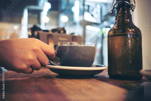 Closeup image of a woman holding coffee cup in modern cafe